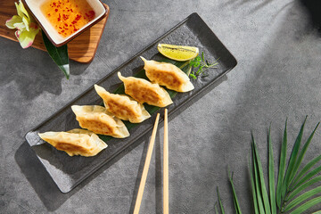 Pan-fried gyoza with seafood filling, bright overhead, rectangular slate serving plate