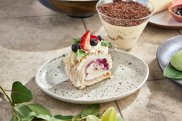 Meringue roulade with berry swirl and cream, bright daylight, angled plate composition