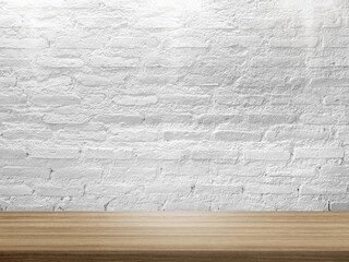 empty wooden table top in foreground with rustic white brick wall and light from above at...