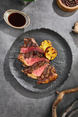 New York strip steak with grill marks, moody lighting, overhead on textured dark plate