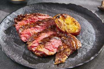 Bavette steak with grilled potato, bright lighting, overhead composition for professional menus