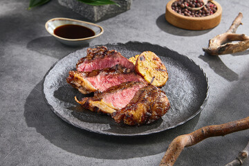 New York steak with grilled potato on rustic slate plate, bright lighting, angled composition