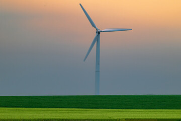 Wind Turbine in Green Fields Against Soft Orange Sunset Sky – Sustainable Energy Landscape