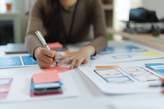 Ux designer writing notes on sticky notes while working on a mobile app wireframe