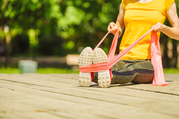 Girl doing exercise outdoor, using resistance fit band.