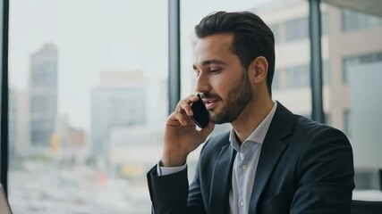 A smiling businessman talks on his phone while working on his laptop - Powered by Adobe