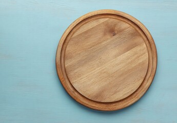 A round, light-brown wooden cutting board sits on a pale blue wooden surface
