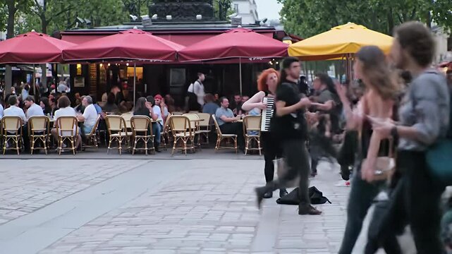 Lively square accordionist performs as blurred pedestrians pass outdoor caf?s