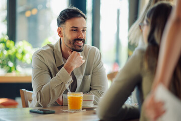 Smiling man enjoying conversation with friends in cafe