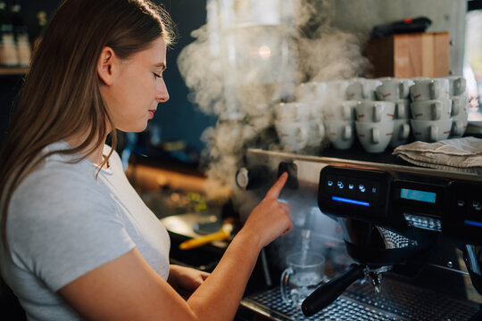Barista preparing coffee with professional machine in cafe