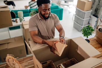 Man packing books into cardboard box, moving into new apartment