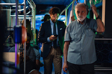 Businessman using smartphone on a bus at night