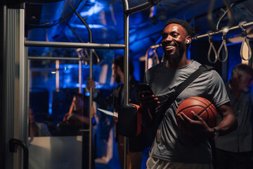 Smiling basketball player using smartphone on night bus ride