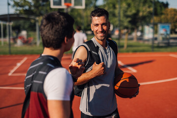 Obraz na płótnie Canvas Two basketball players talking after match on outdoor court