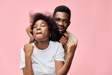 Joyful couple celebrating together with enthusiastic expressions against a pink background,...