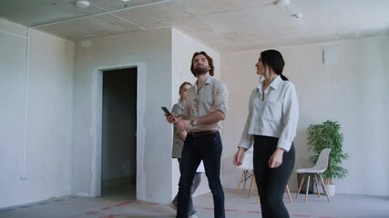 Young couple tours a new, unfurnished apartment with a real estate agent, capturing details on their mobile phones while exploring the space