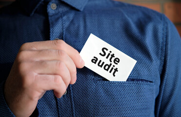 A man in a blue shirt holds a sign with the text of Website audit in one hand