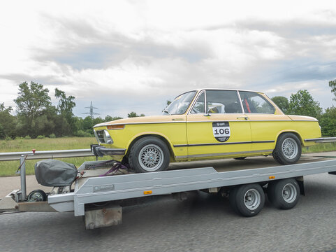 1 may 2025, Germany. 1970&rsquo;s car. Yellow oldtimer BMW 1802 or BMW 2002 on a trailer on German highway. German oldtimer car with stickers of the Wilder Kaiser oldtimer rallye.