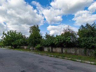 A street with a fence and trees on both sides of it