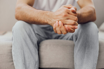 Relaxed man sitting comfortably with hands clasped, showcasing emotional strength and self-assurance in a modern interior setting. Perfect for lifestyle themes.