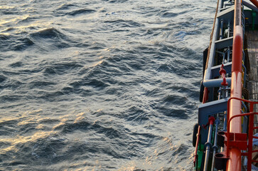 The side of the ship where the alleyway is located. Massive orange crash rail protects the area below from the damage during cargo and towing operations. Cargo pipes are located underneath