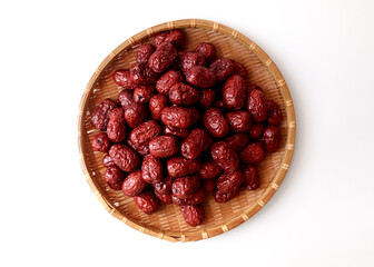 Dried red jujubes in a bamboo tray. White background.