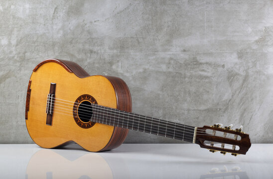 Musical instrument - half-side view classical guitar concrete wall on a white table