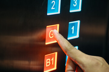 close up of finger pressing ground floor button in elevator