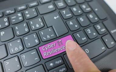 Cyber resilience key on a gray keyboard. Finger pressing key