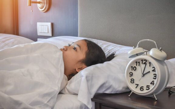 Sleepless girl child suffering sleep disorder, insomnia problem, mental health illness. Young asian school kid, keeping awake with anxiety or nightmare fear on bed at late night in home bedroom