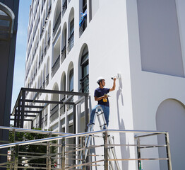 A technician installs a CCTV camera on the facade of a residential building