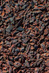 Close-up of crushed black and red gravel fragments, detailed textured surface with sharp edges, industrial material background or abstract texture