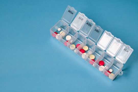 Plastic pill organizer containing colorful pills for each day of the week. medical background with space for text