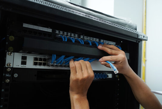 A maintenance technician works in a server room with a fiber optic hub