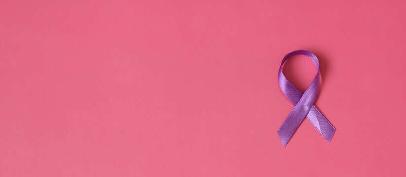 Purple ribbon lying on pink background symbolizing support for many important causes
