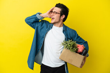 Russian Man making a move while picking up a box full of things isolated on yellow background...