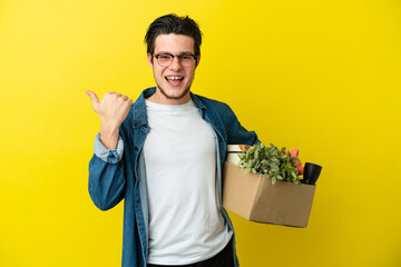 Russian Man making a move while picking up a box full of things isolated on yellow background...