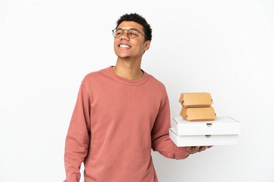 Young African American man holding a burger and pizzas isolated on white background thinking an idea while looking up - Powered by Adobe