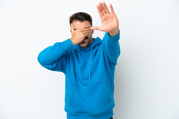 Young caucasian man isolated on white background making stop gesture and covering face