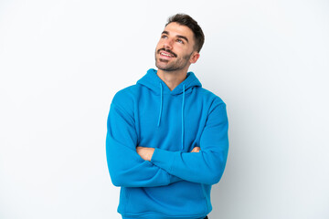 Young caucasian man isolated on white background looking up while smiling