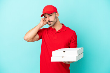 Delivery caucasian man picking up pizza boxes isolated on blue background having doubts