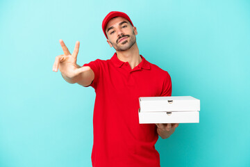 Delivery caucasian man picking up pizza boxes isolated on blue background happy and counting three...