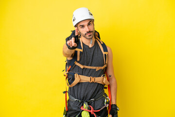 Young caucasian rock climber man isolated on yellow background showing and lifting a finger