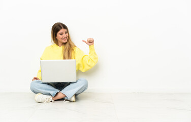Young woman with a laptop sitting on the floor proud and self-satisfied
