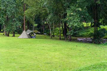 nature camping or glamping cabin tent on green grass lawn campground with water stream shady and tree garden with camper family holiday vacation at khao laem national park in ka teng cheng waterfall