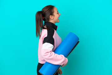 Sport Ukrainian woman going to yoga classes while holding a mat laughing in lateral position