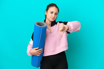 Sport Ukrainian woman going to yoga classes while holding a mat showing thumb down with negative...