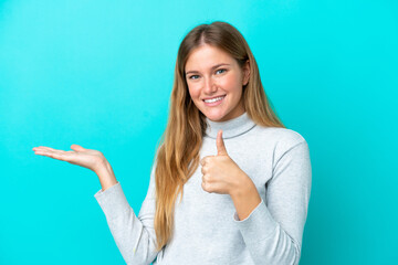 Young blonde woman isolated on blue background holding copyspace imaginary on the palm to insert an...