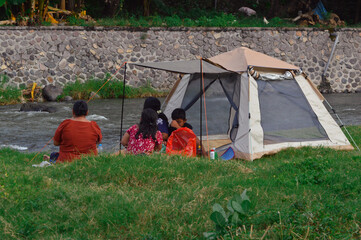 A calm moment as the family sits near the tent, enjoying snacks and drinks while casually observing...