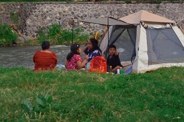 As the mothers chat and the girl sits relaxed, the young boy enthusiastically points at something...